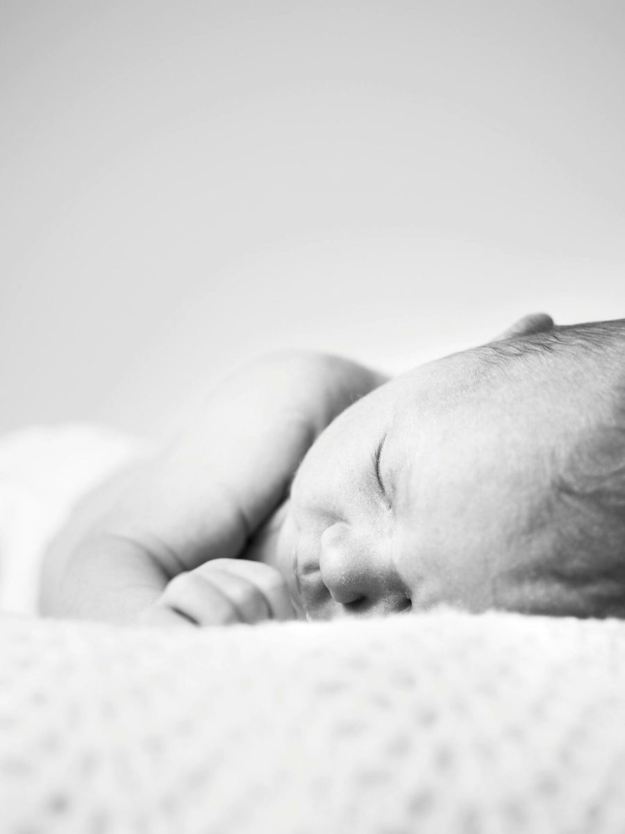 A serene black and white photo of a sleeping newborn baby wrapped in a soft blanket.